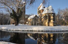 Pottendorf castle ruins in winter with snow and reflection in the water.