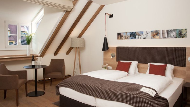 Comfortable hotel room with double bed, seating area and sloping roof.