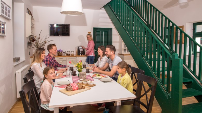 Family sitting at a table in a modern dining room with a green staircase.