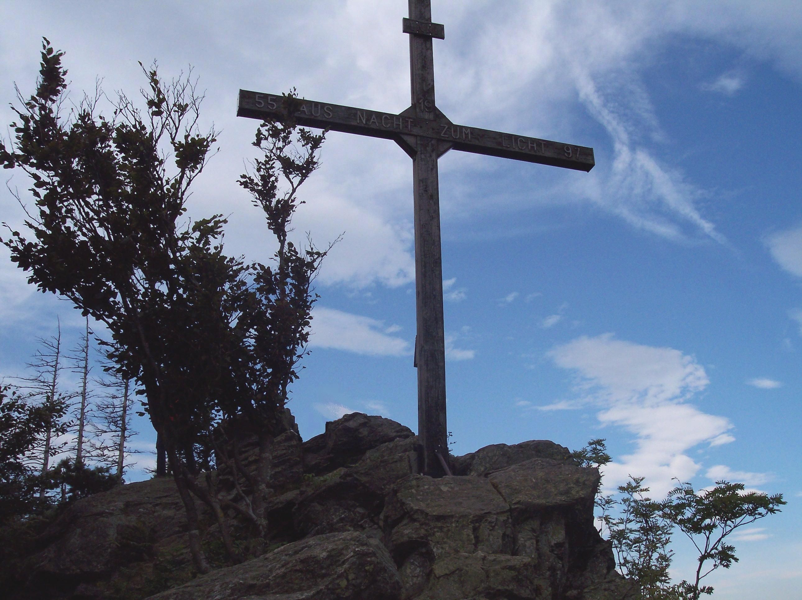 A summit cross on a rock with a blue sky in the background.