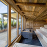 Modern sauna with wood paneling, dark tiles and glass front with a view of the outdoors.