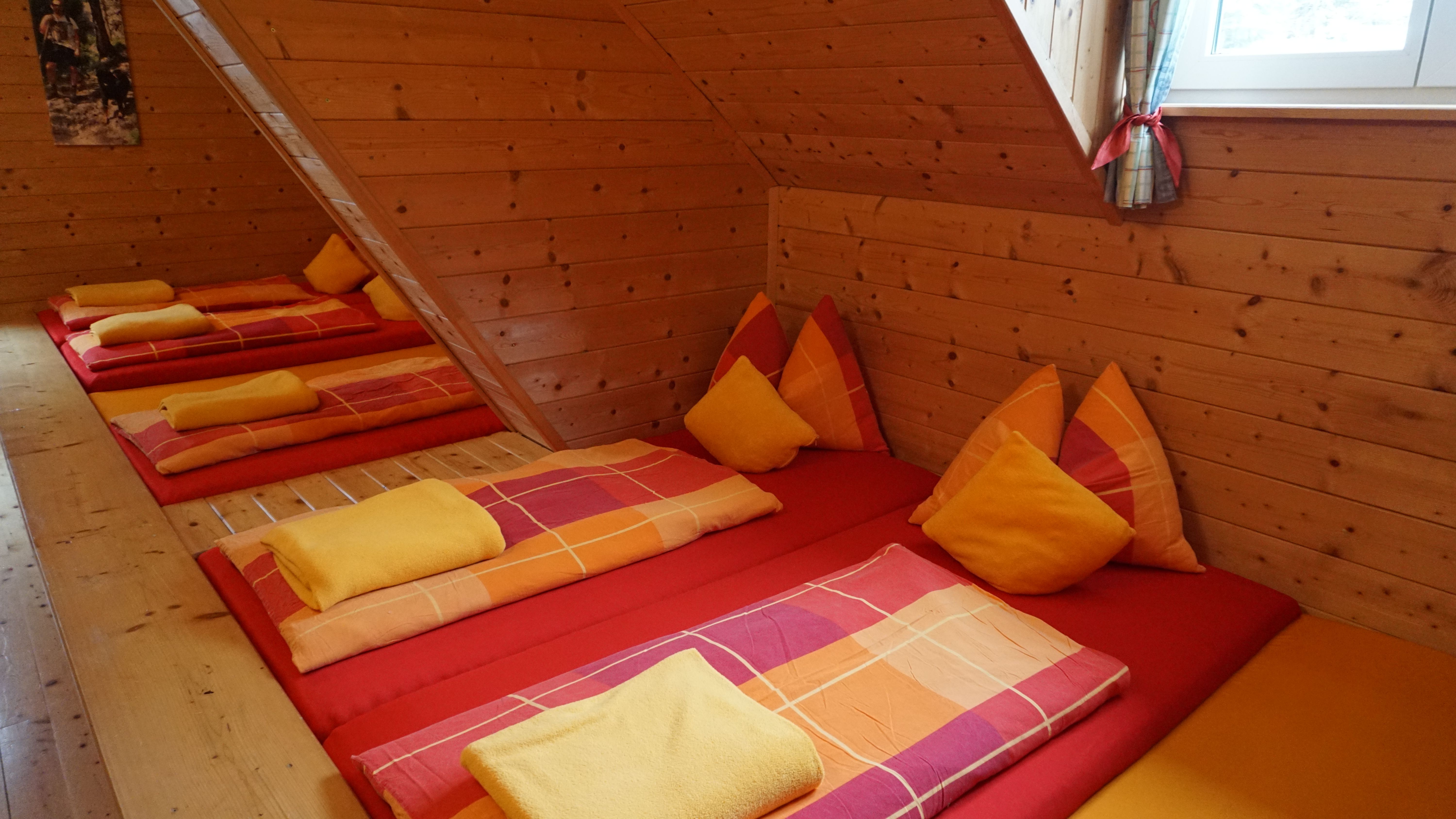 Cozy bedroom with wooden walls and colorful beds in a mountain inn.