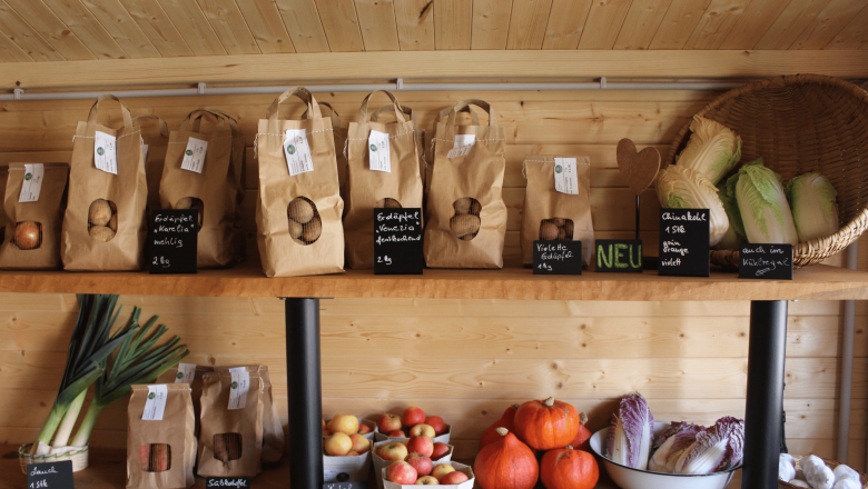 Shelf with potatoes, apples, pumpkins and vegetables in paper bags and baskets.