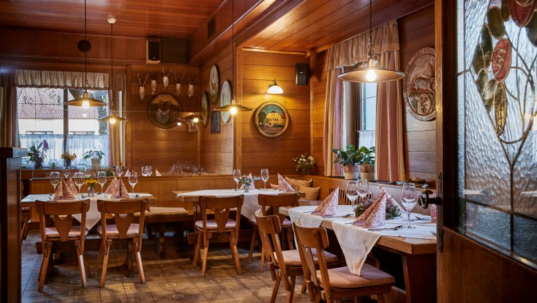Cozy, wood-paneled tavern with set tables, chairs and decorative elements on the walls.