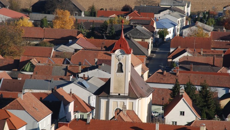 Aerial view of the Getzersdorf parish church with surrounding houses and fields in the fall.