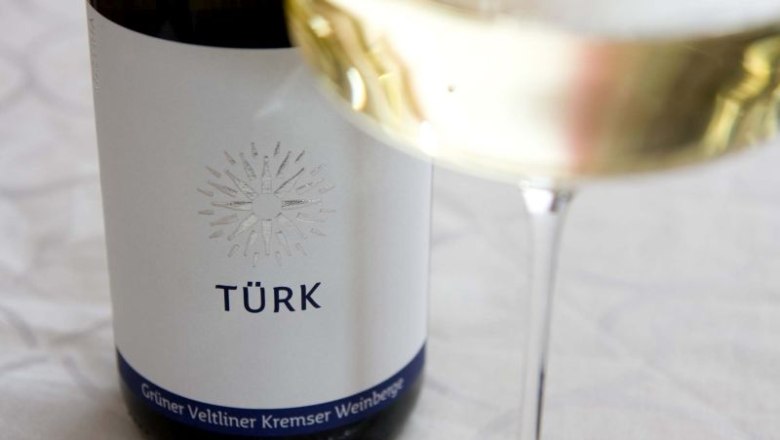Wine bottle with label 'T&Uuml;RK' and wine glass with white wine.
