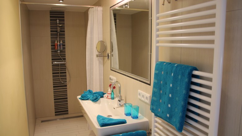 Modern bathroom with shower, washbasin and blue towels.