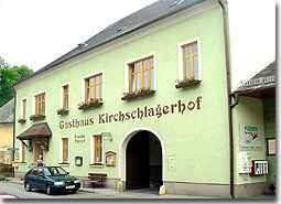 A traditional inn with a green façade and the inscription 'Gasthaus Kirschlagerhof'.