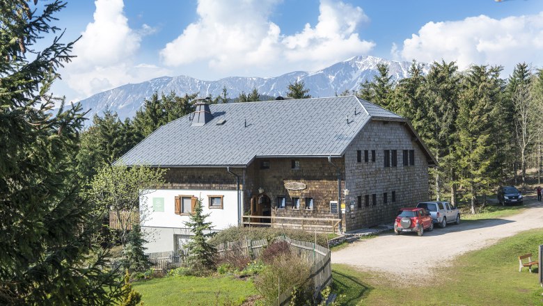 Öhler shelter, © Wiener Alpen, Franz Zwickl A rustic shelter in a mountainous landscape with trees and cars in the foreground.