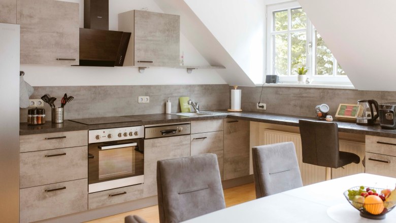 Modern kitchen with gray cabinets, dining table and fruit bowl.