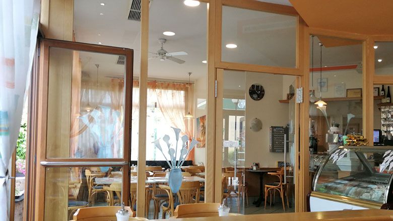 Interior view of a cozy café with wooden furniture and large windows.
