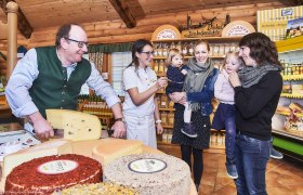People in a cheese dairy, tasting cheese and smiling.