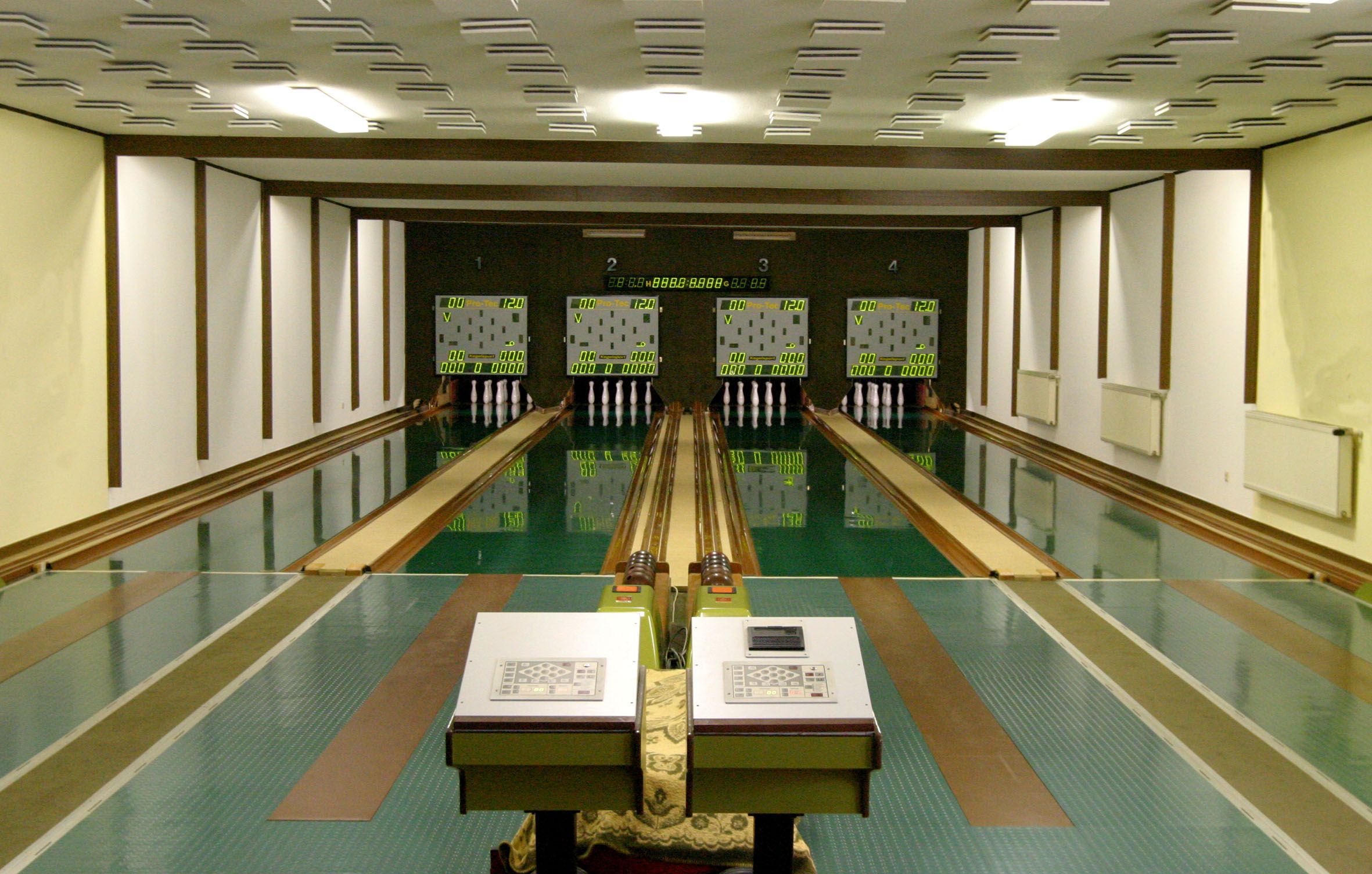 Interior view of a bowling alley with four lanes and scoreboards.