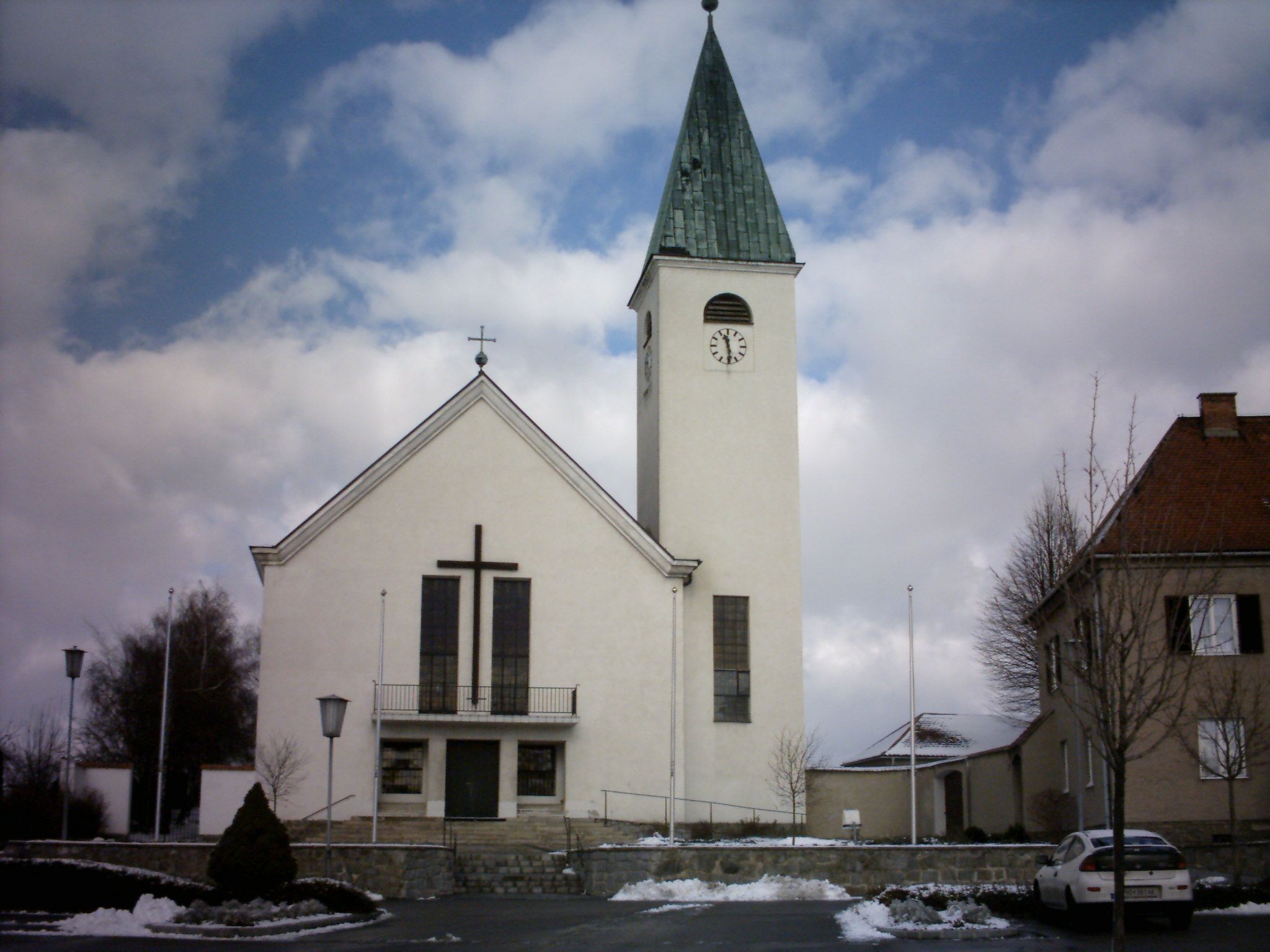 Church with tower and clock in Sigmundsherberg, surrounded by snow and clouds.