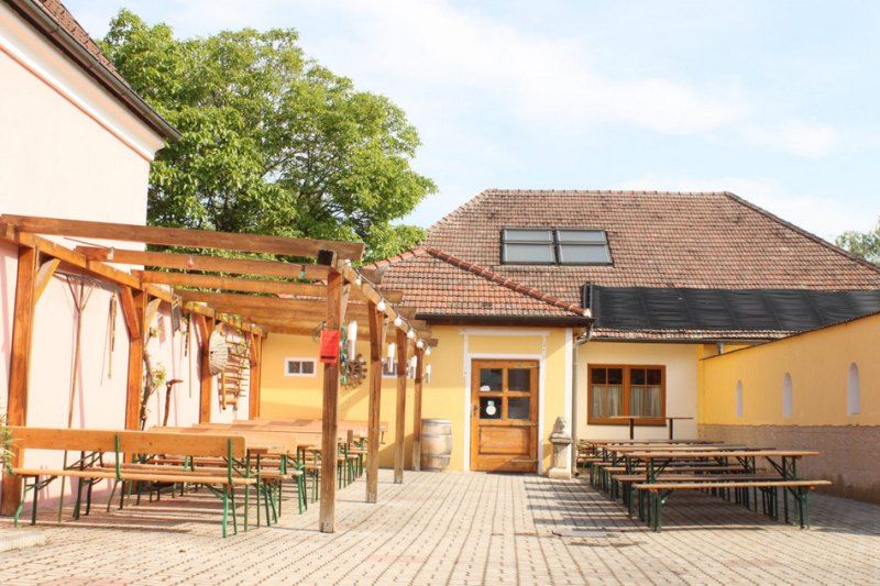 Inner courtyard of a wine bar with wooden benches and tables under a pergola.