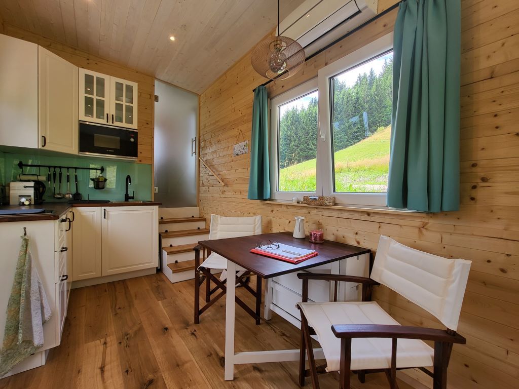 Small kitchen with dining area and window with view of meadow and forest.