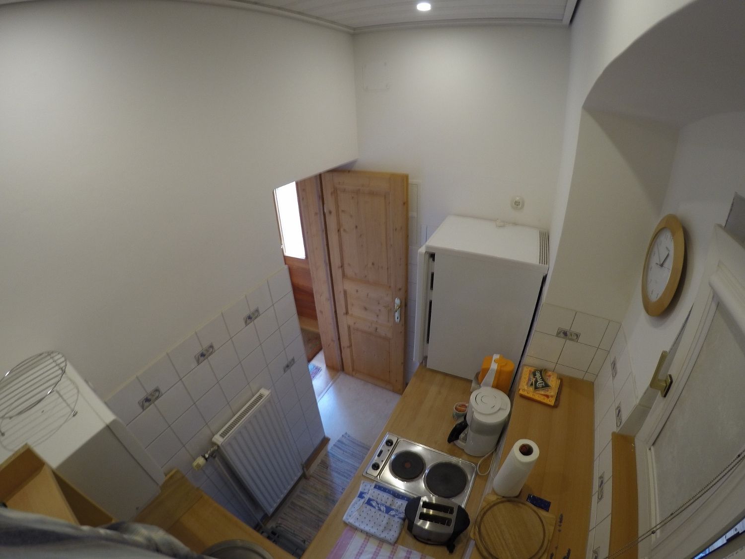 Small kitchen with stove, fridge and wooden door.