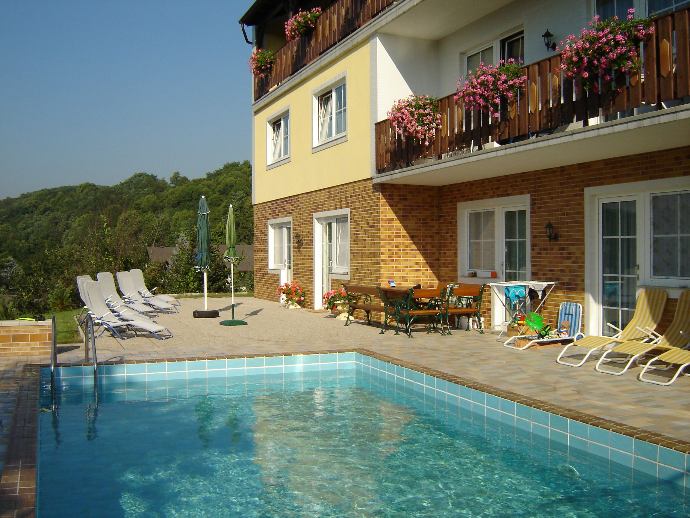 Exterior view of a guesthouse with pool and sun loungers.