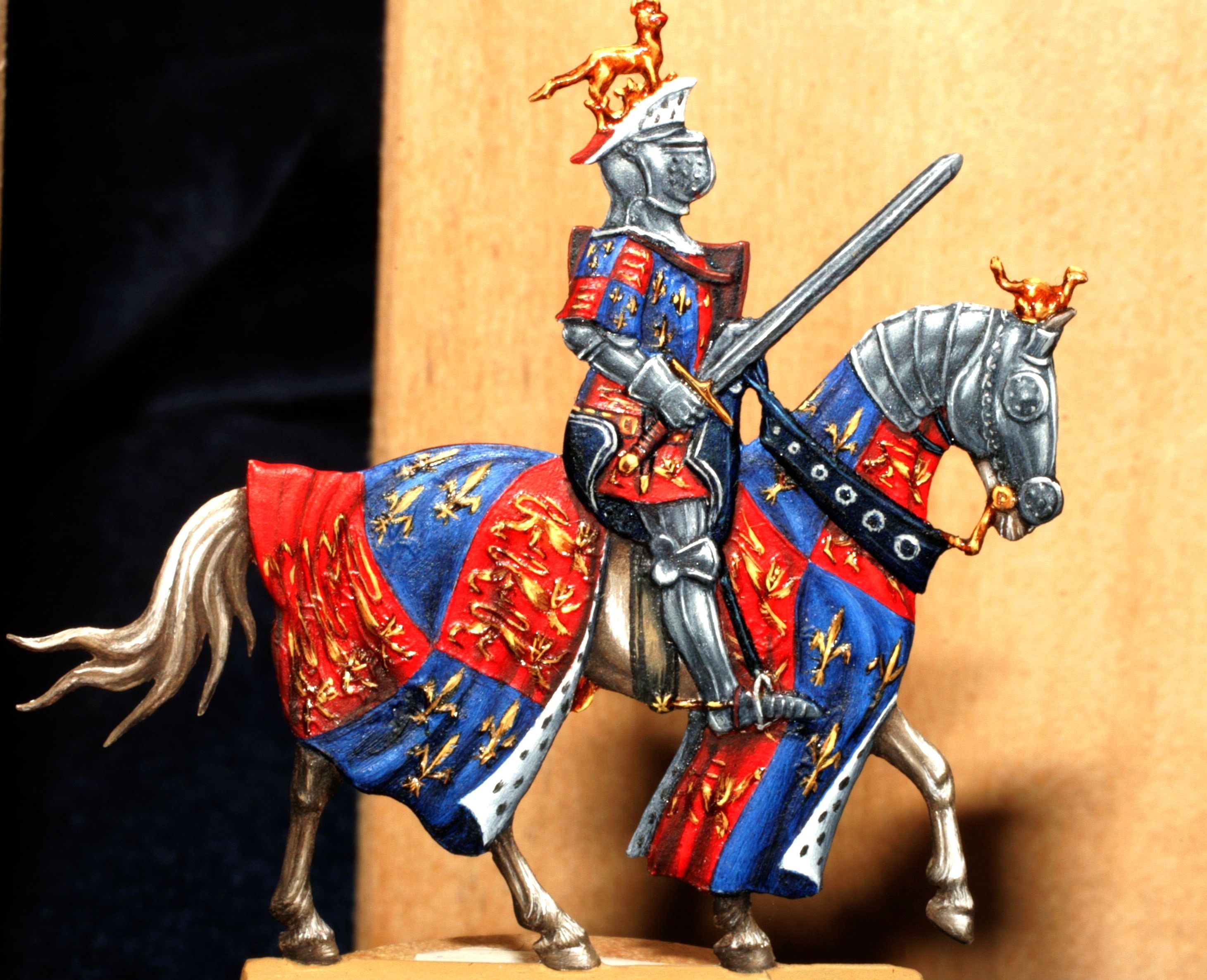 Pewter figure of a knight in armor on a horse with a colorful tabard.