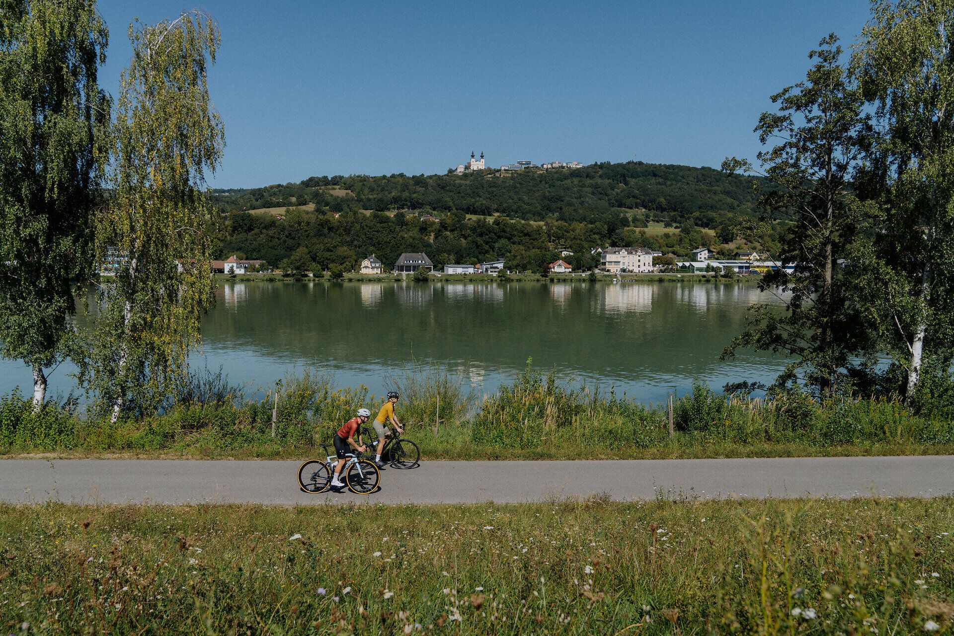 2 cyclists on the Danube cycle path in the Nibelungengau with a view of the Danube and Maria Taferl