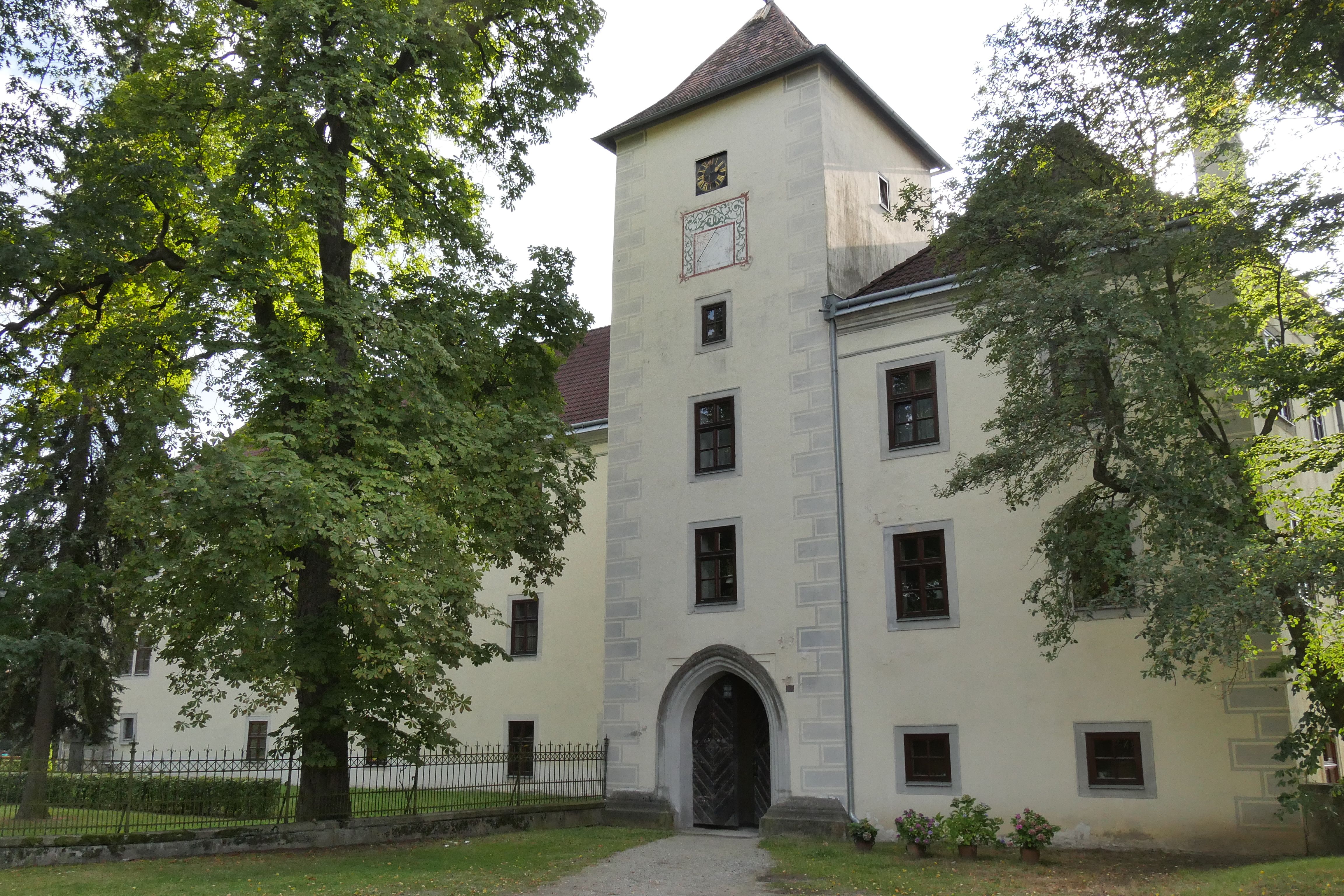 Historic building with tower and trees in the foreground.