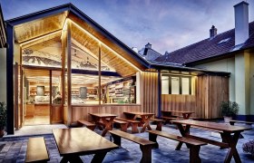 Modern winery with wooden elements and outdoor area at dusk.