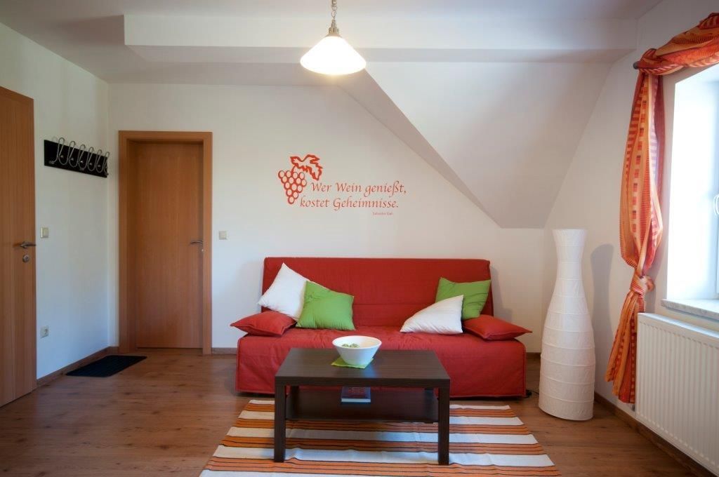 Cozy guest room with red sofa, cushions, lamp and wall quote.