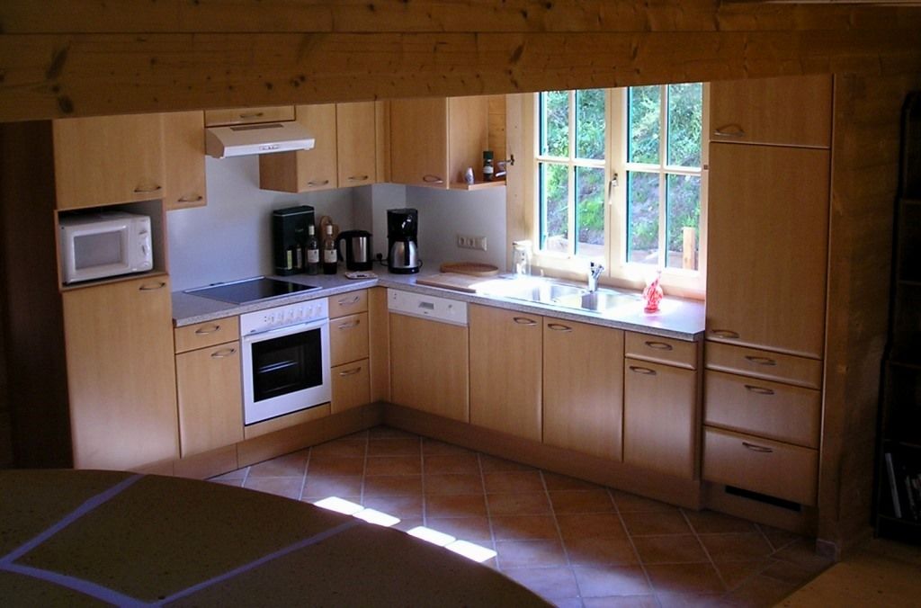 Modern kitchen with wooden cupboards, stove, sink and window.