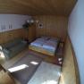 A cozy bedroom with wooden walls, a double bed, a sofa and a carpet on a wooden floor.