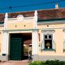 A traditional yellow building with green doors and windows, a bicycle in front of it and a child sitting on the stairs.
