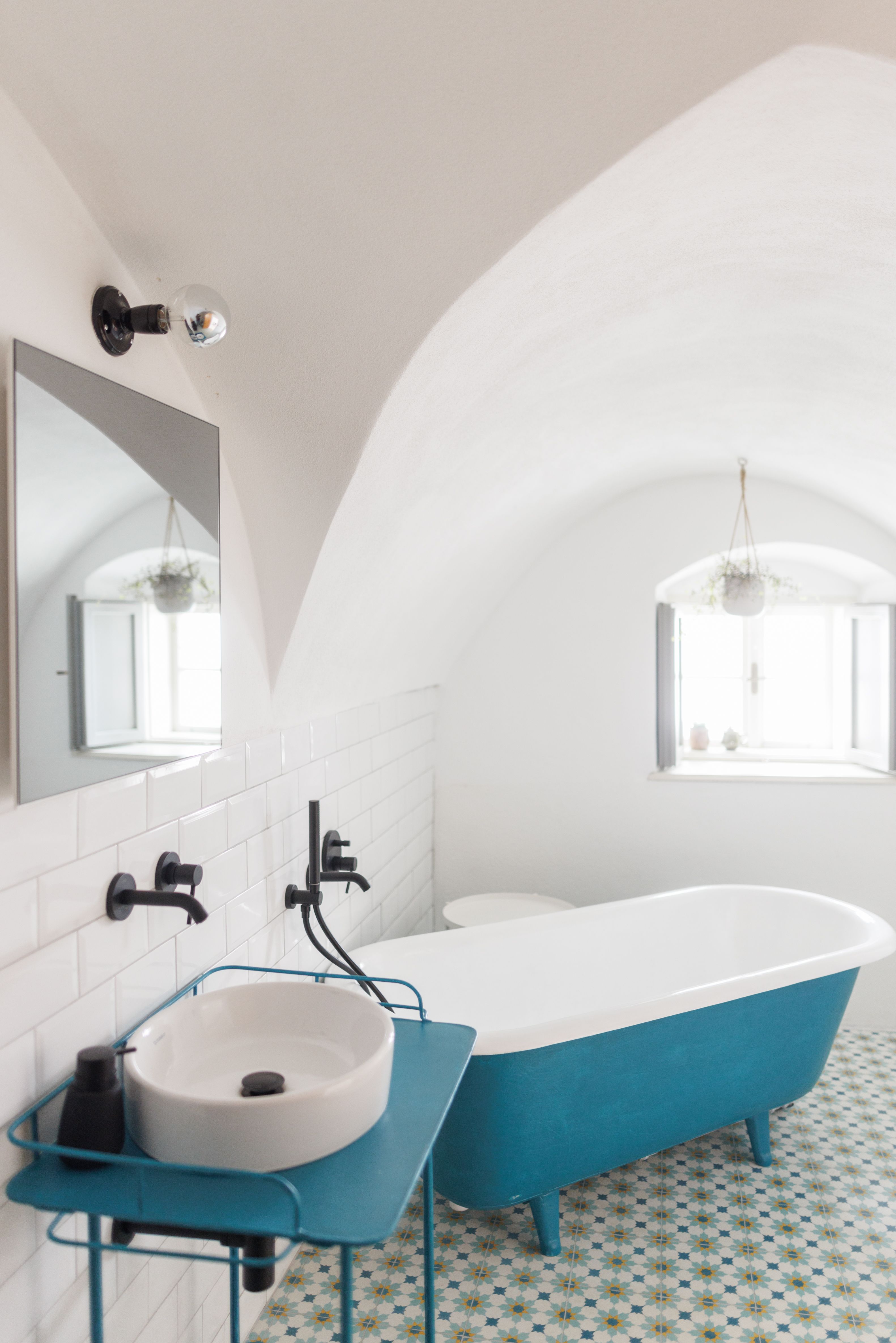 Modern bathroom with blue bathtub and washbasin.