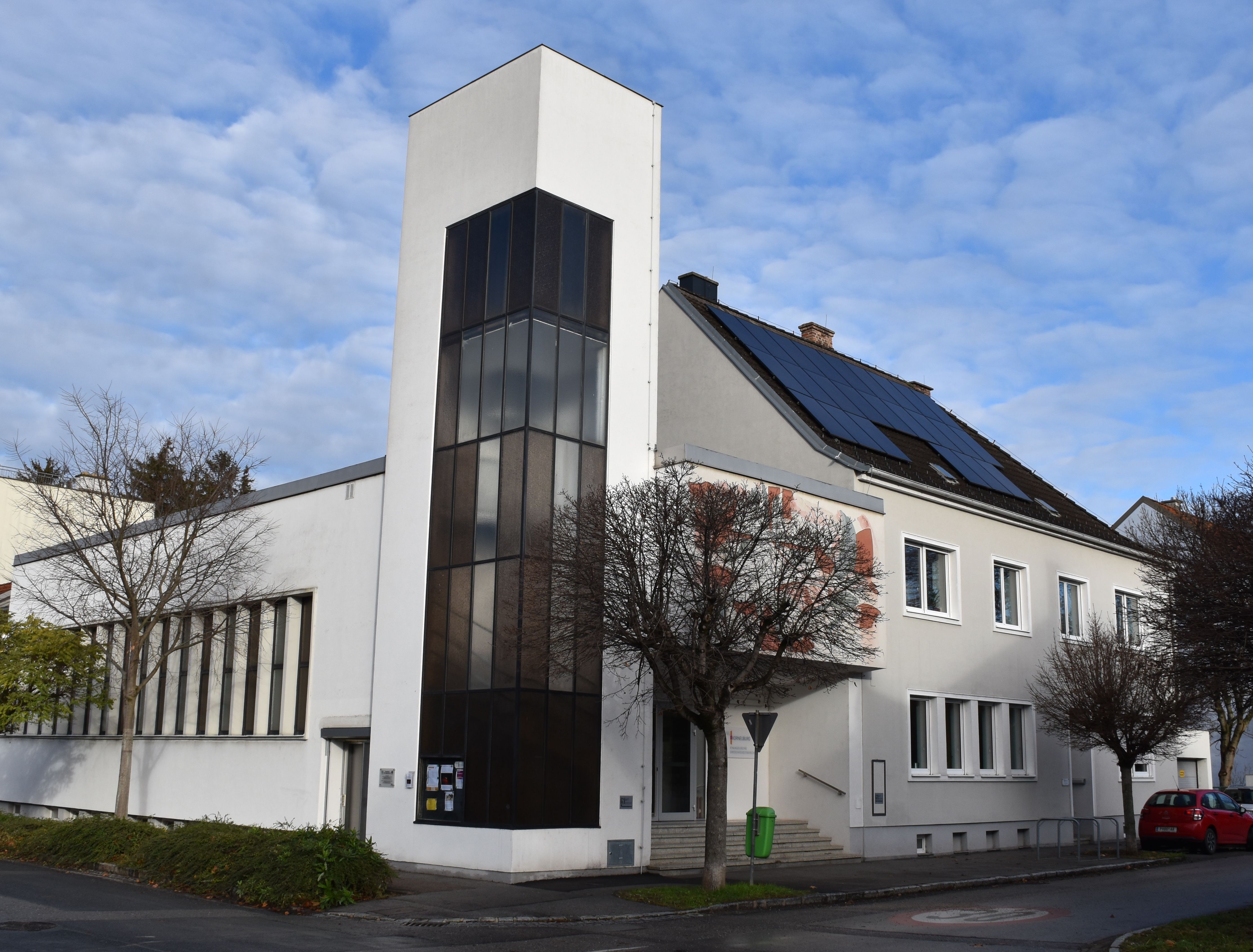 Modern church with a white façade and solar panels on the roof.