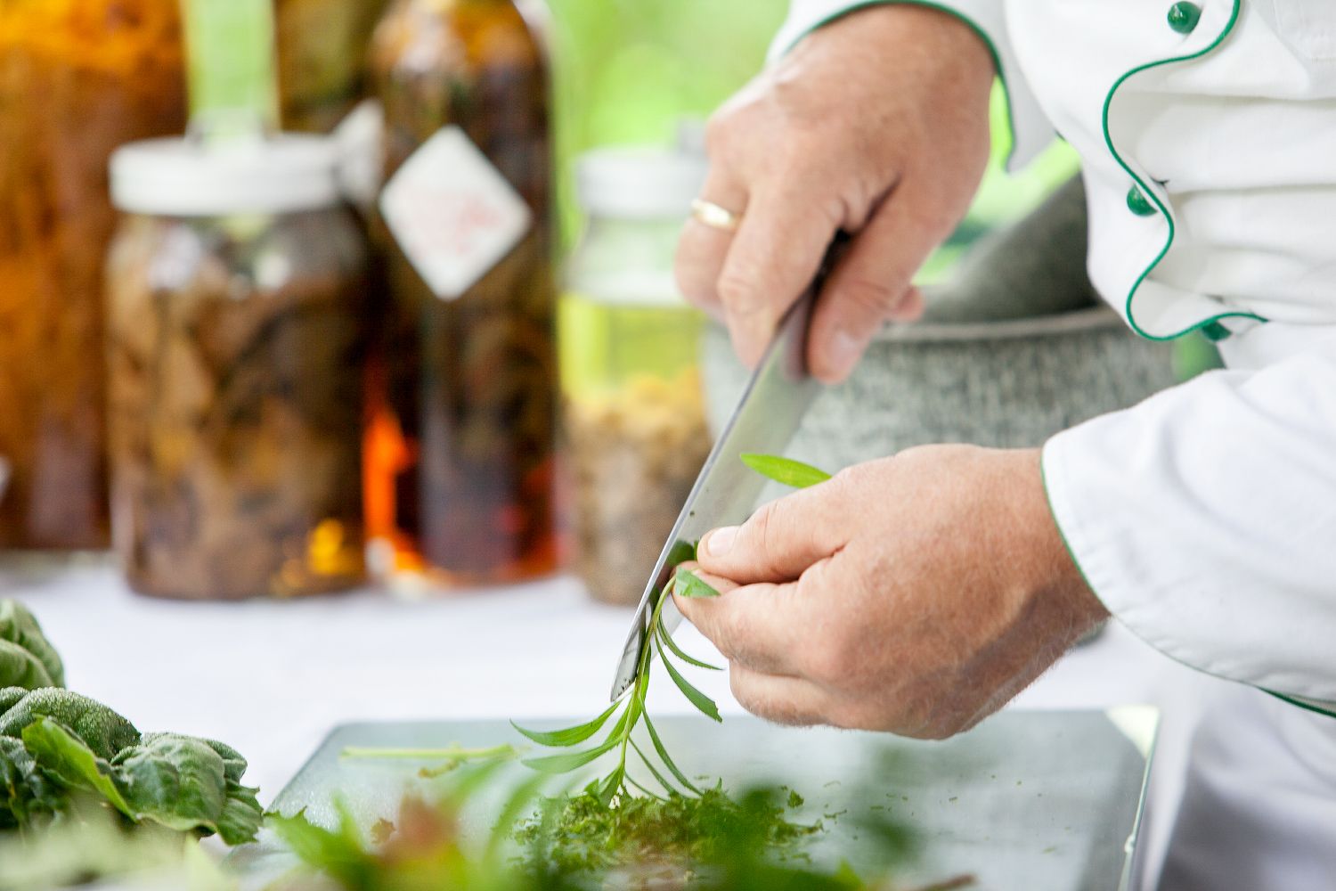Person cuts fresh herbs with a knife.