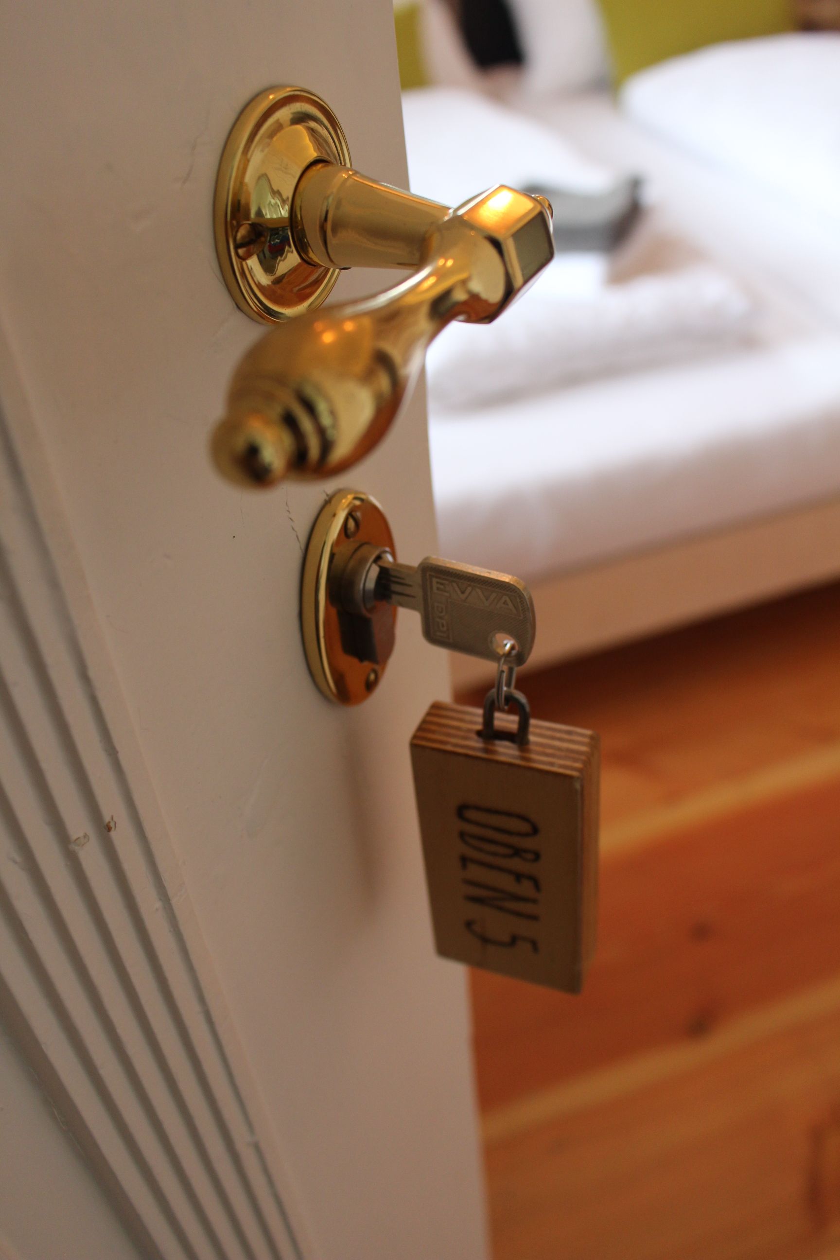 Close-up of a door handle with key and wooden tag with the inscription 'OBEN 5'.