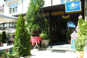 Entrance to a restaurant with plants and signs.