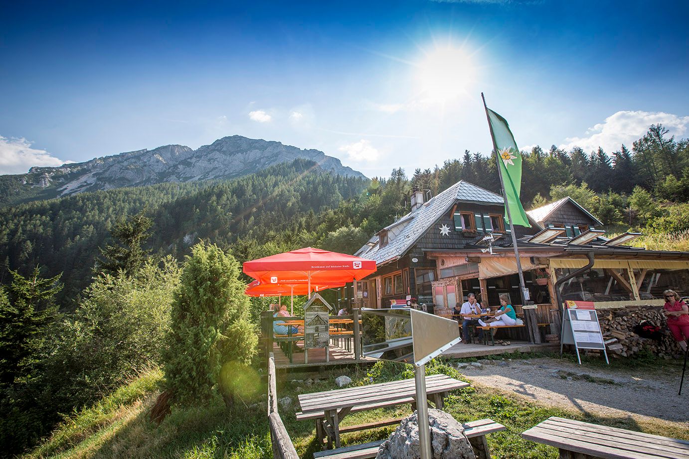 Edelweiss hut on the Schneeberg with parasols and mountain backdrop.