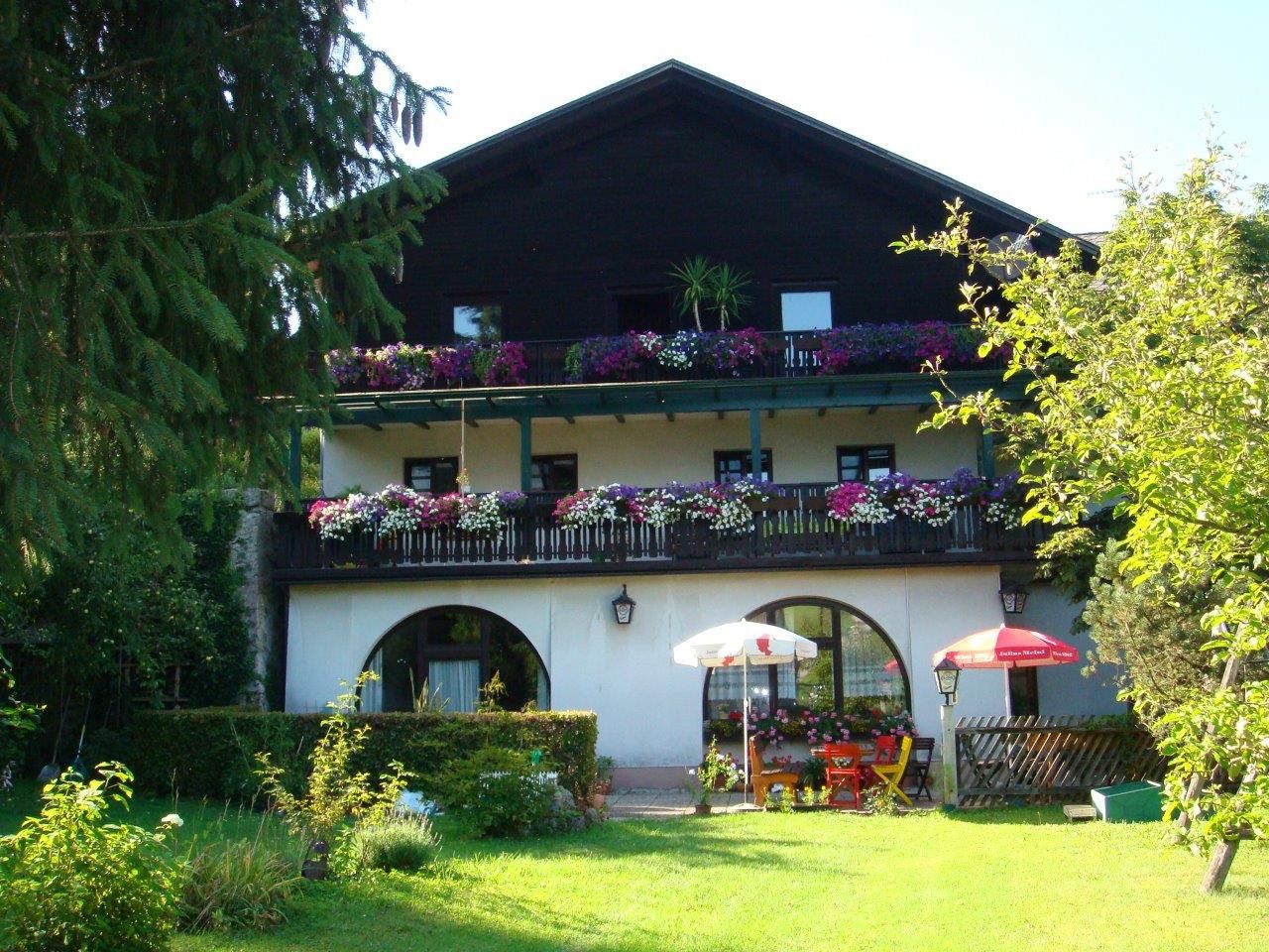 A traditional inn with a wooden balcony and flowers in Scheibbs, surrounded by a green garden.