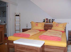 Cozy bedroom with double bed and yellow-red bed linen.