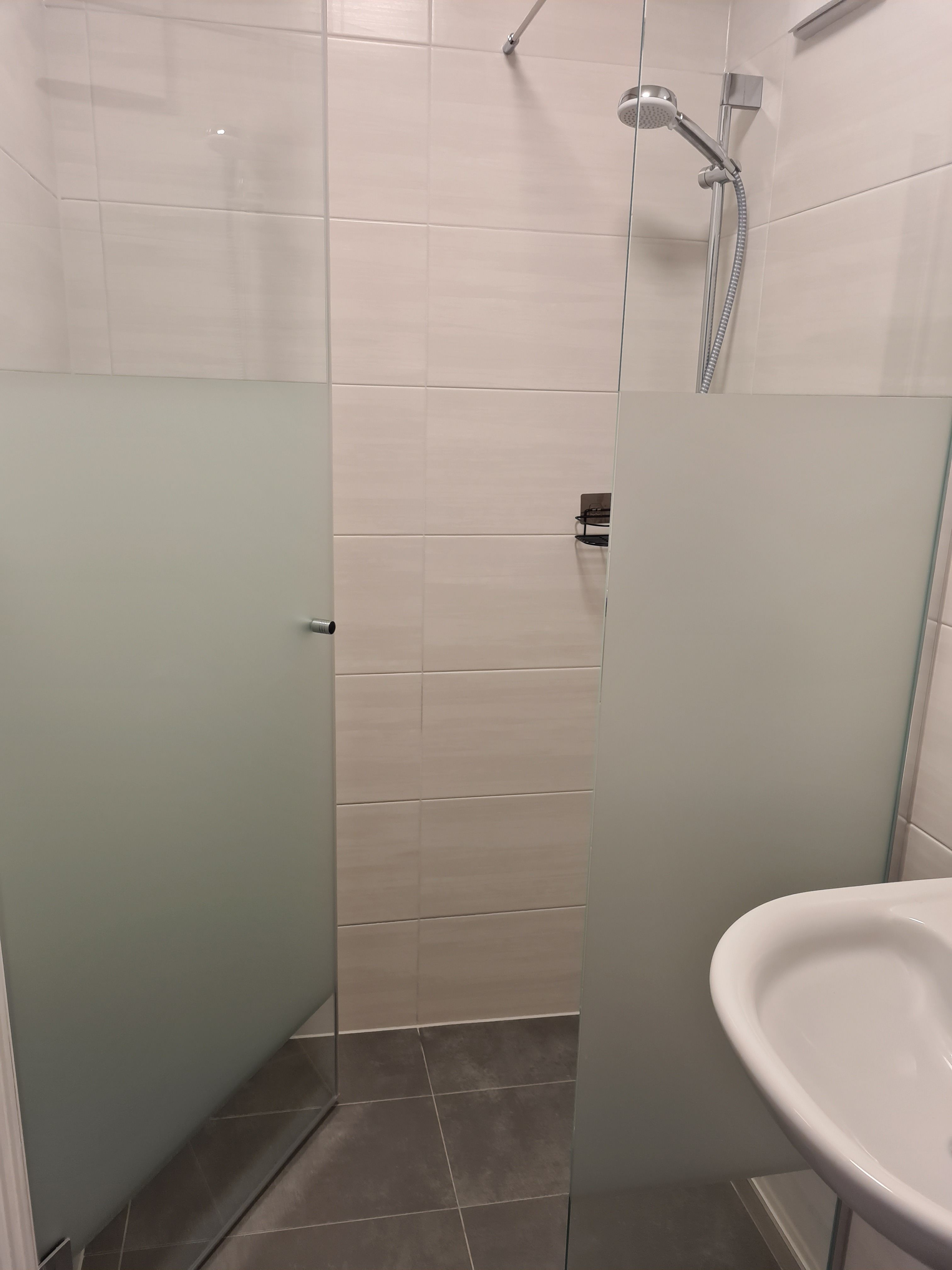 Modern shower with glass walls and shower head in a bathroom.