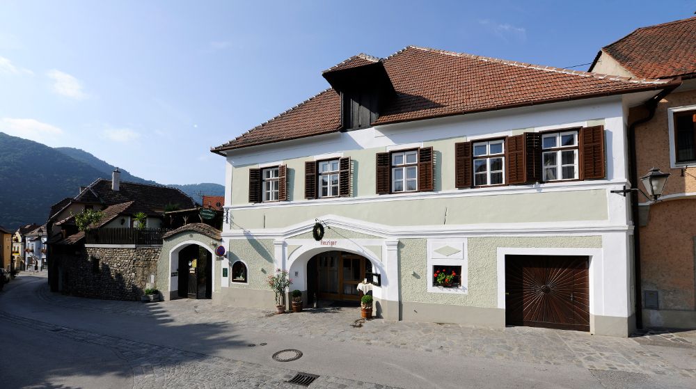 Traditional house with green façade and brown shutters in a rural setting.