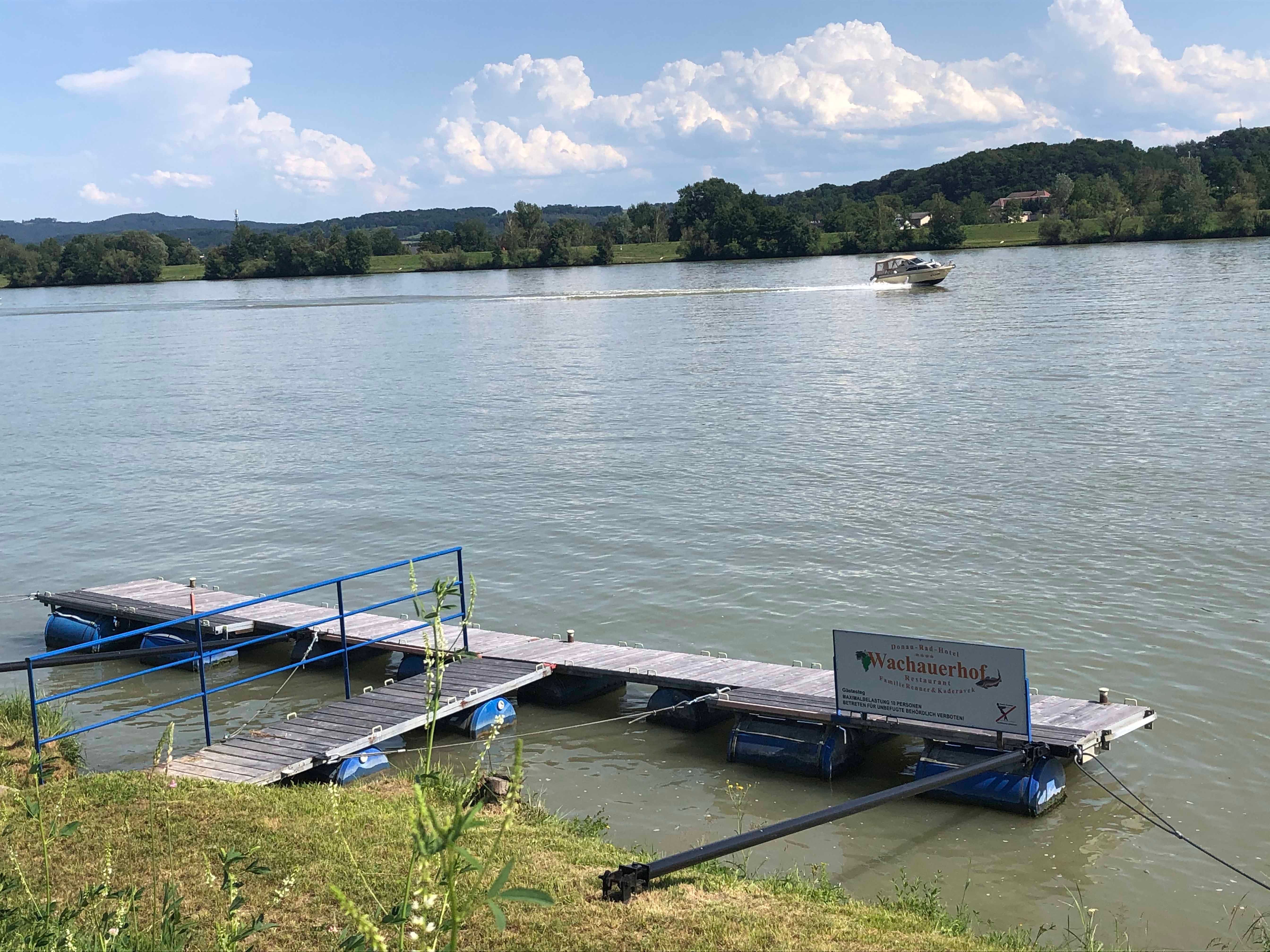Jetty on the river with boat in the background.
