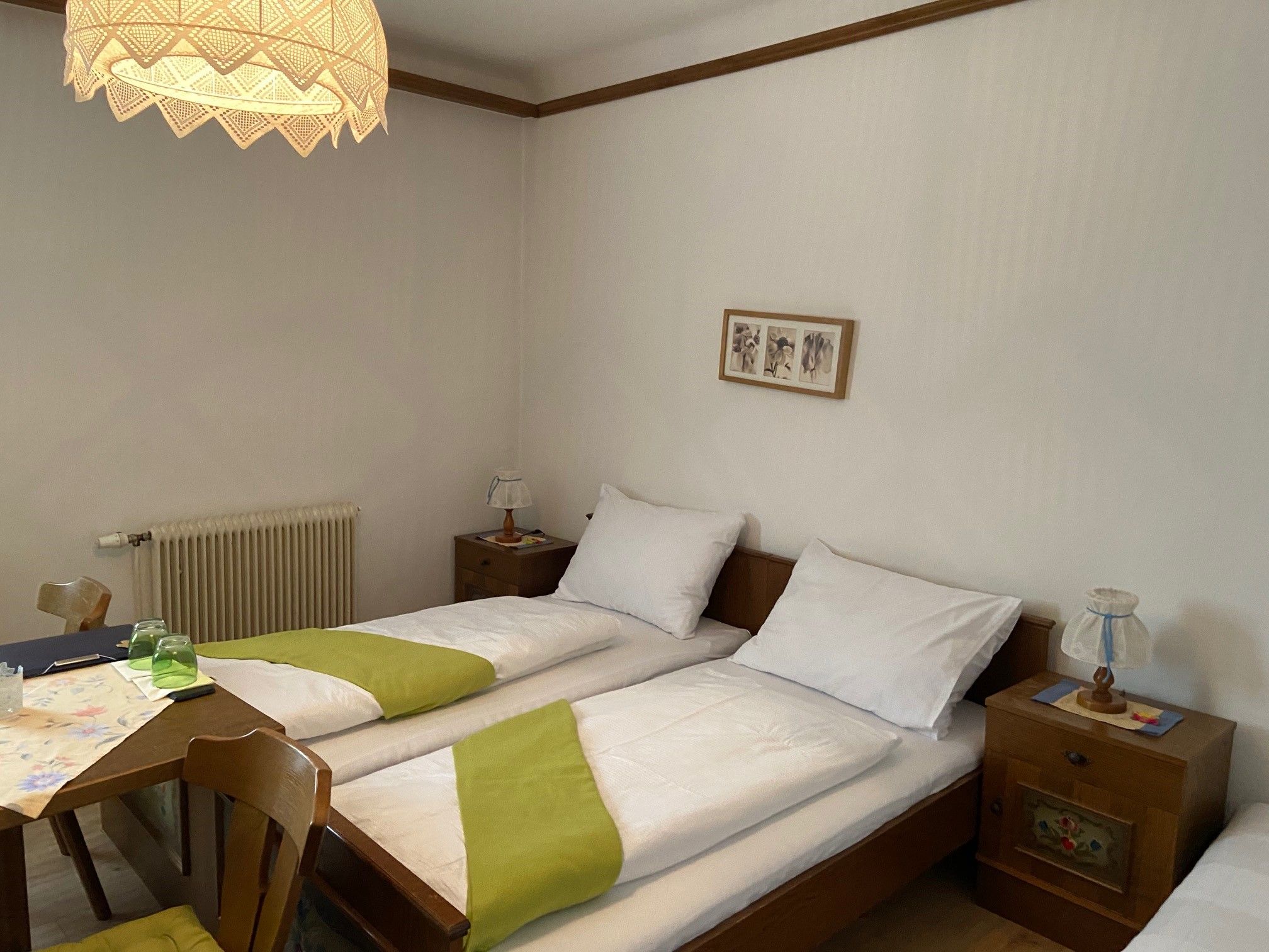 Cozy double room with two single beds, wooden furniture and a decorative lamp.