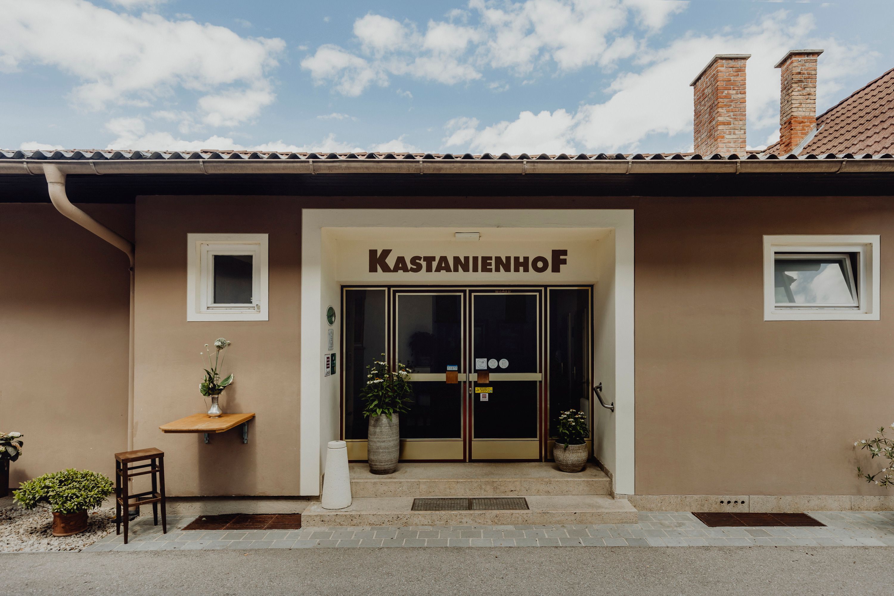 Entrance to the Kastanienhof in Grafenbach with plants and table.