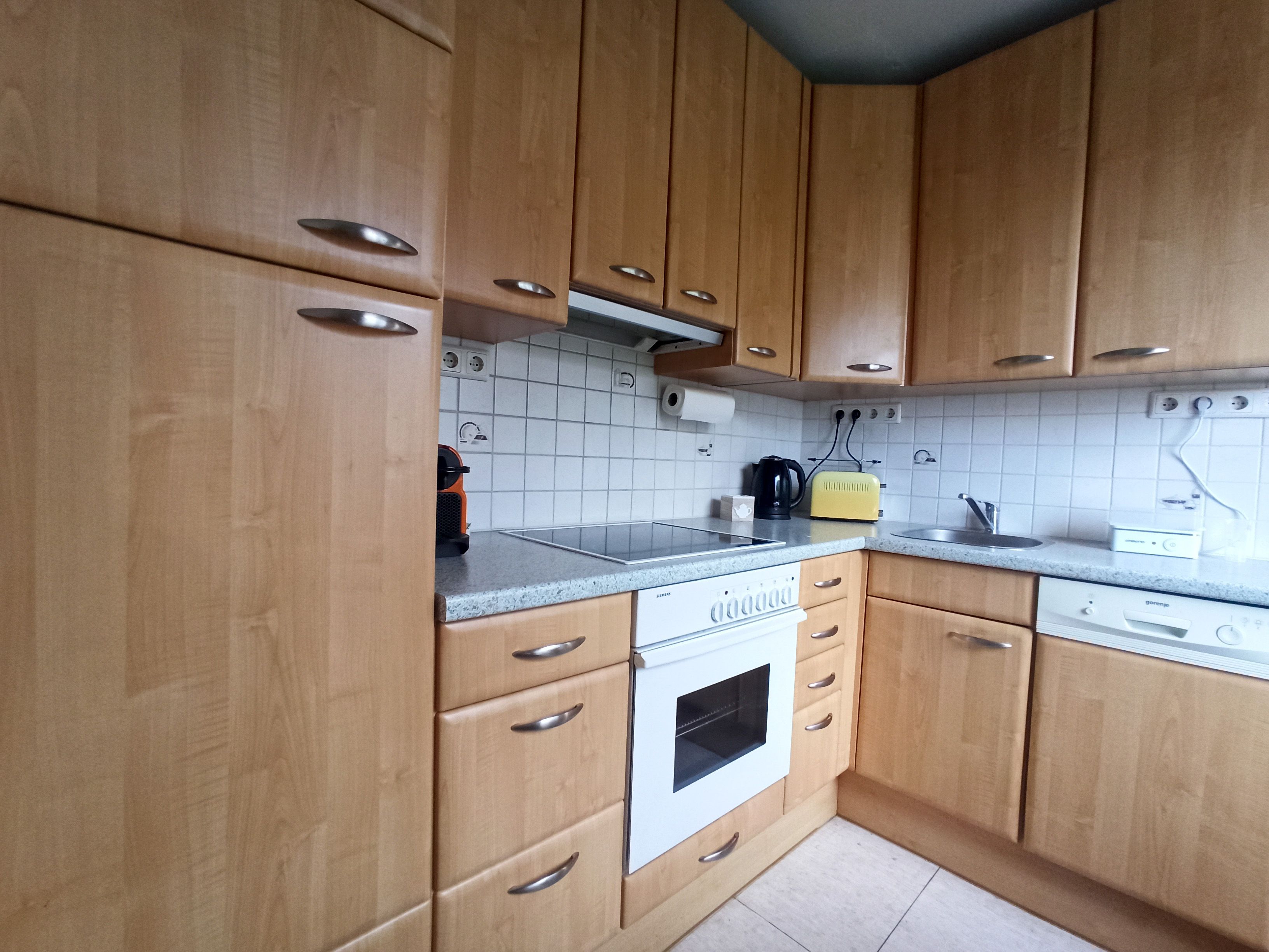 Kitchen with wooden cupboards, stove, sink and worktop.