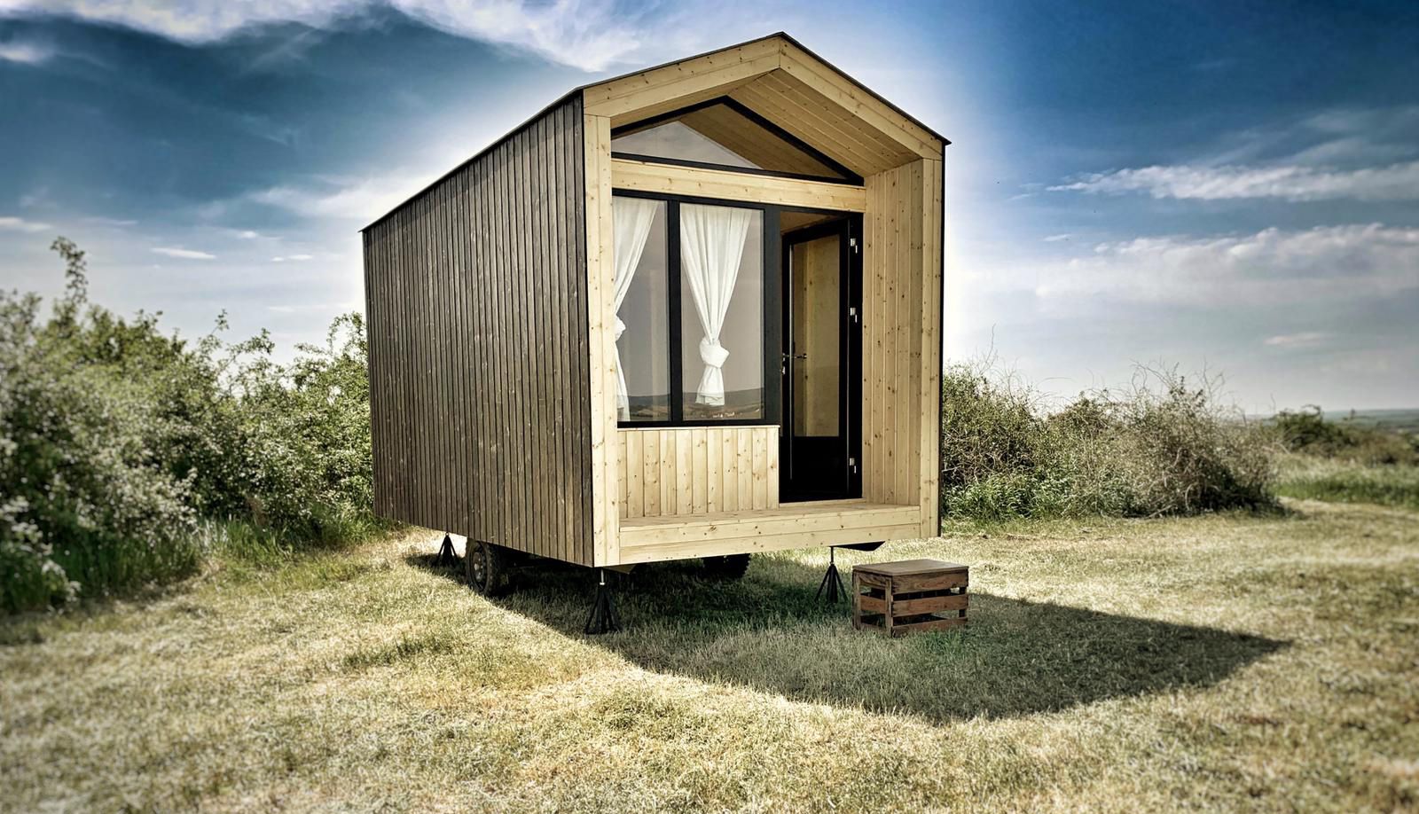 Small wooden hut in a field with a blue sky in the background.
