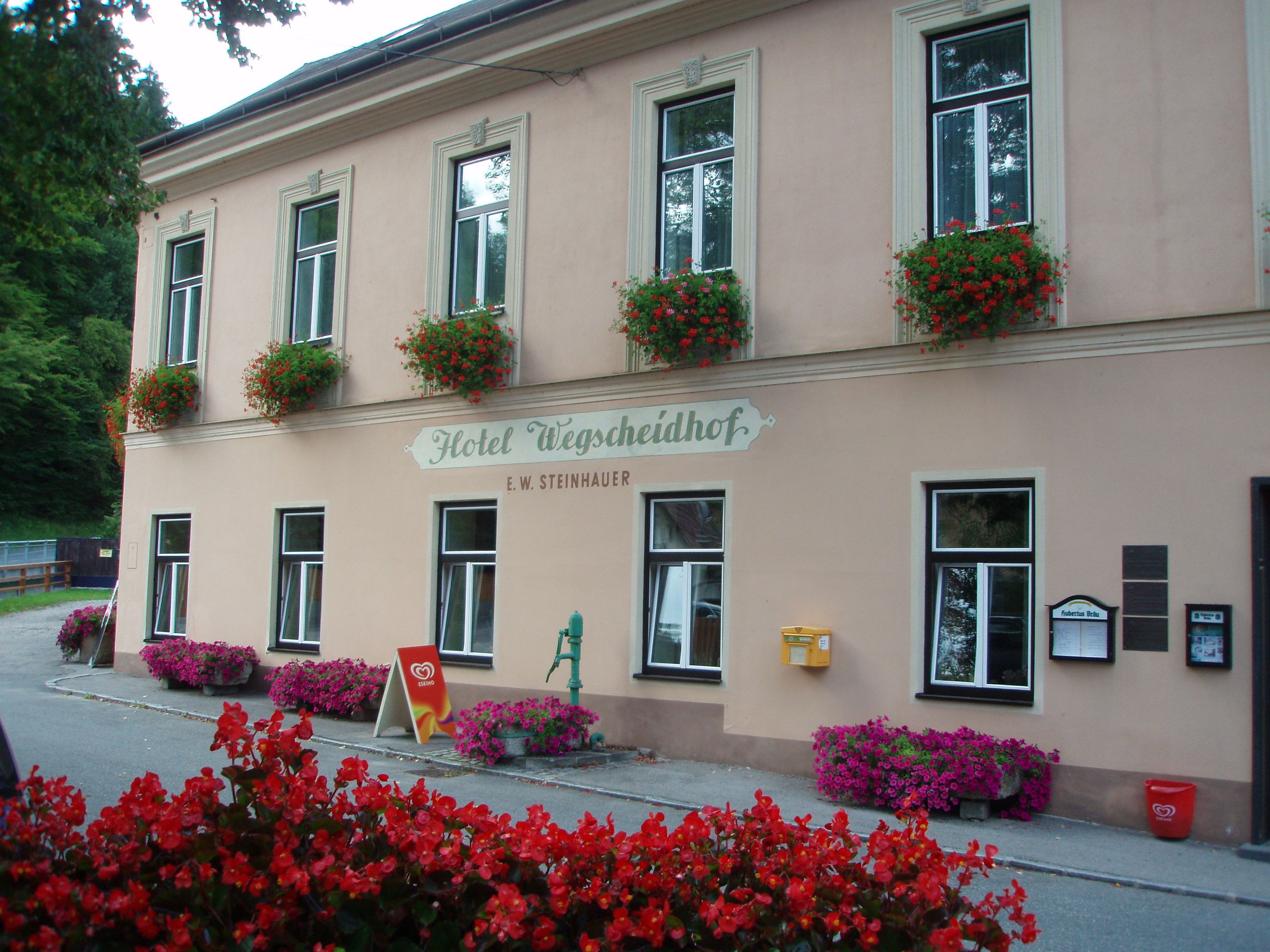 Facade of the Hotel Wegscheidhof with flower boxes and signs.