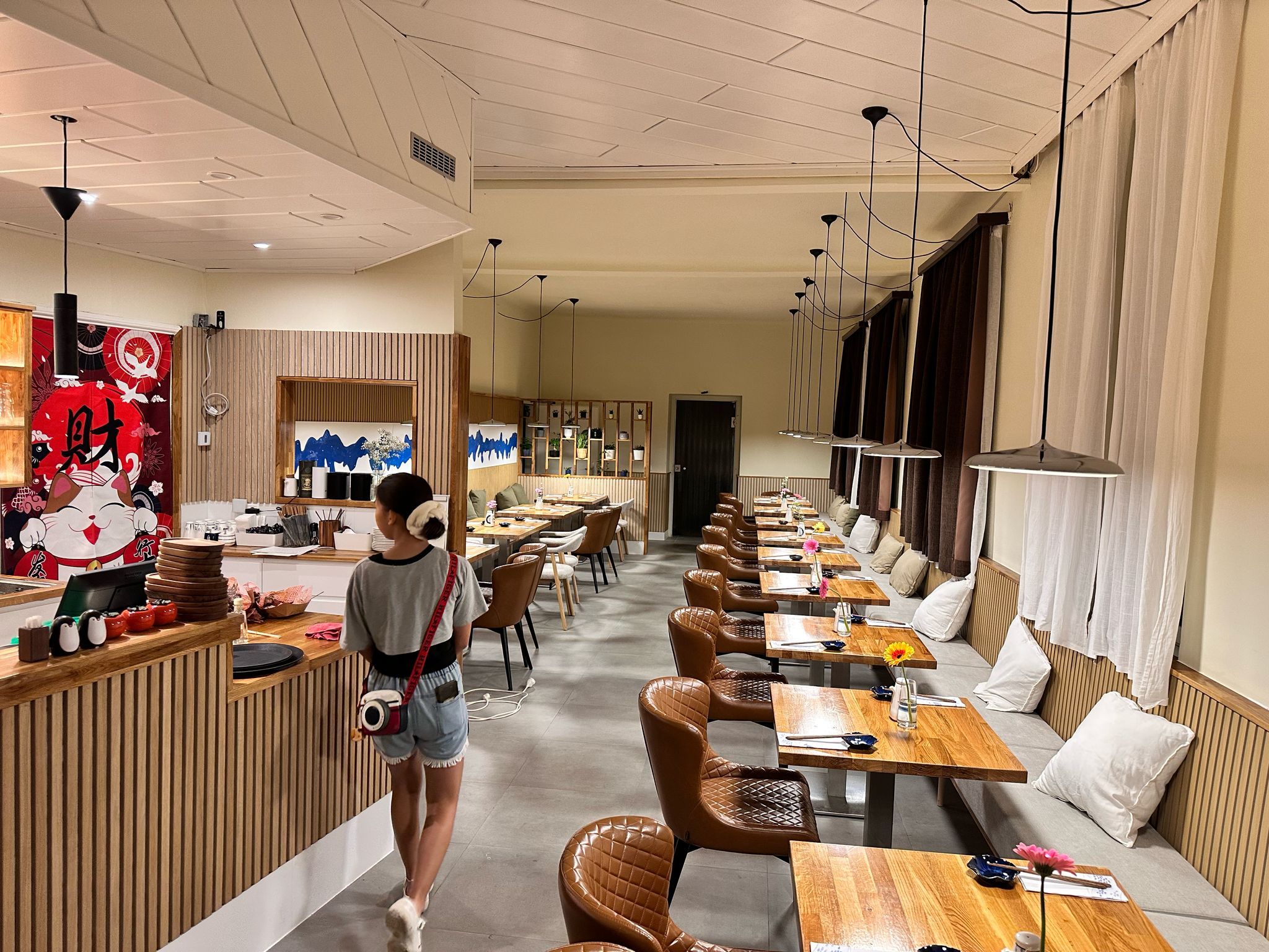 Interior view of a modern restaurant with wooden tables and leather armchairs.