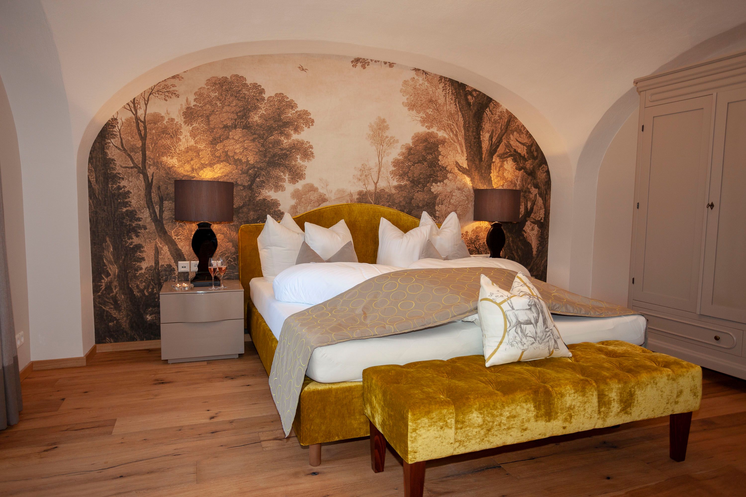 Elegant suite with yellow bed, wall painting and wooden floor in Schloss Luberegg