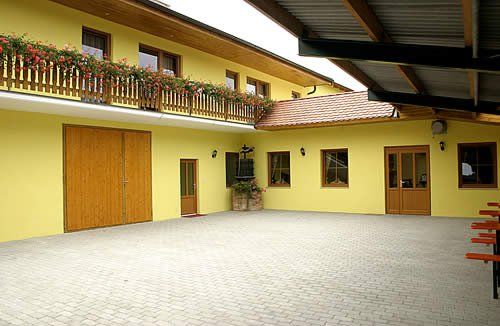 Inner courtyard of a yellow building with wooden doors and balcony with flowers.
