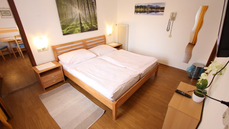 Bright bedroom with double bed, wooden furniture and pictures of nature on the wall.